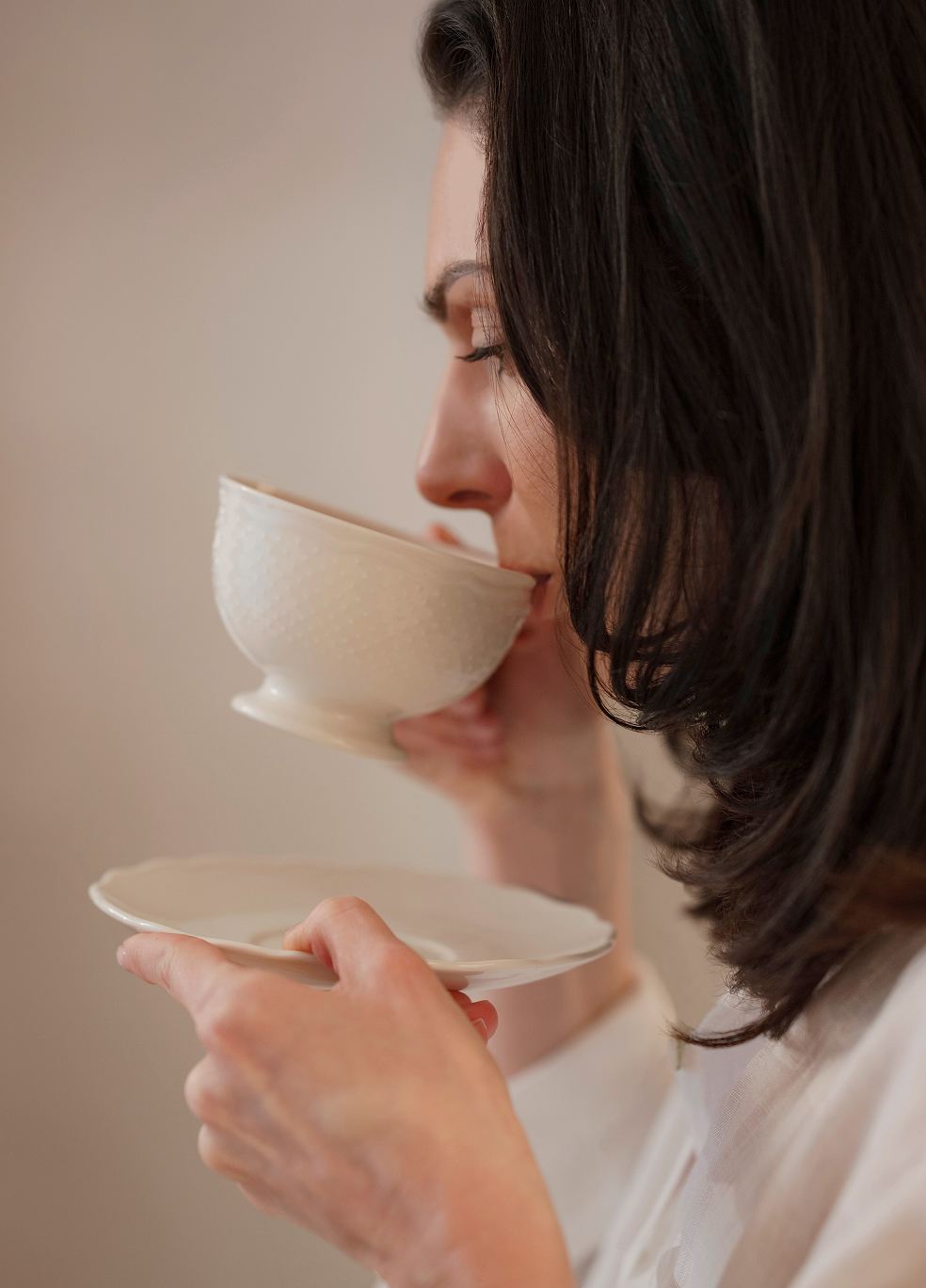 Woman savoring tea from a ceramic cup