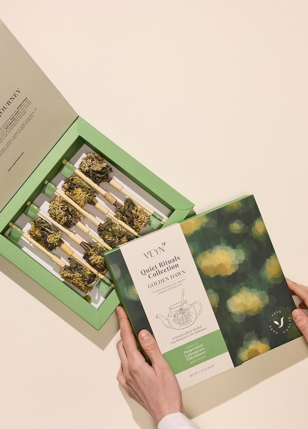 Hands holding open Veyn Quiet Rituals Collection Golden Dawn herbal tea box