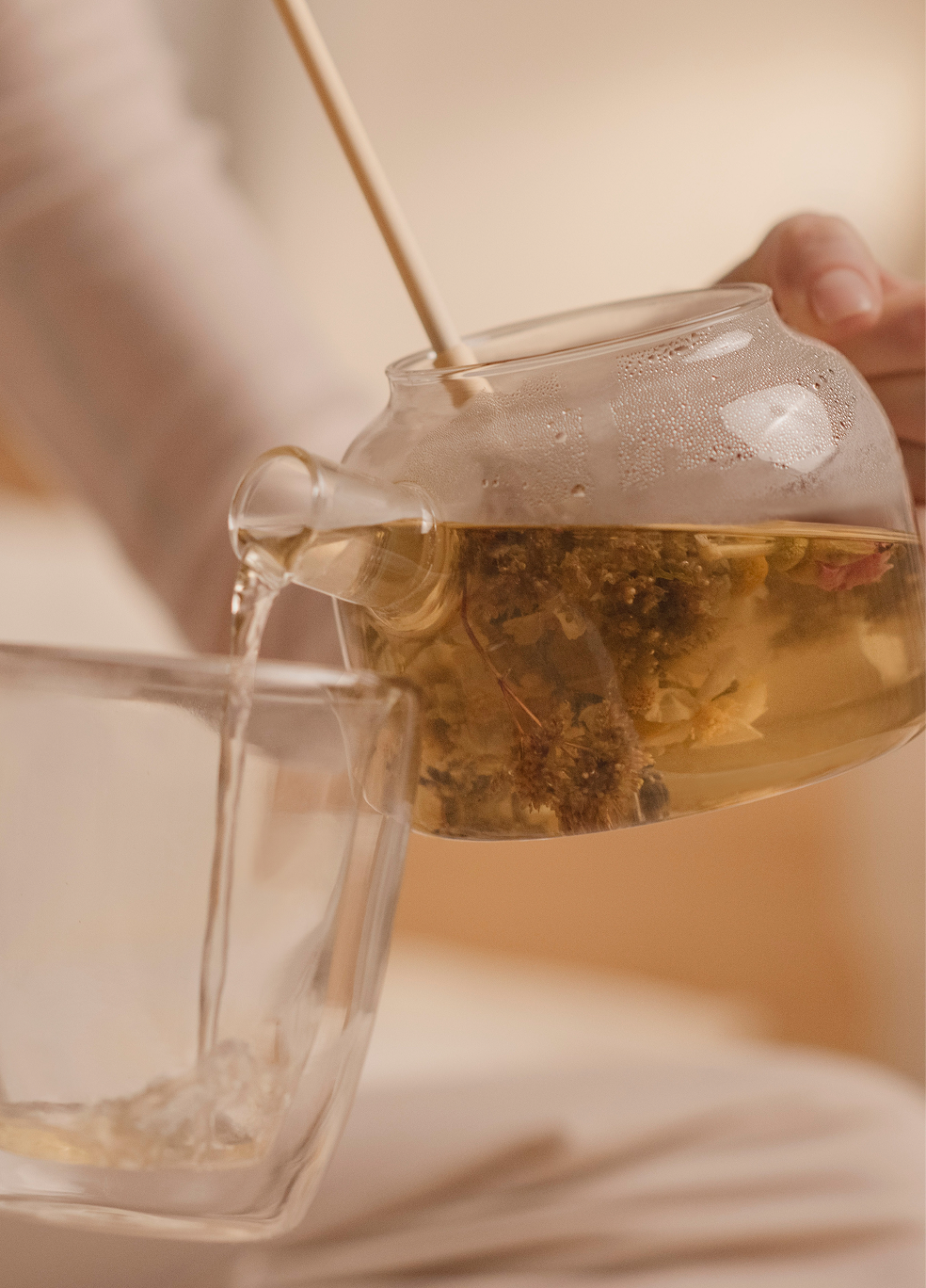 Hand-tied Veyn botanical tea bouquet unfurling in a glass teapot with lavender and chamomile.